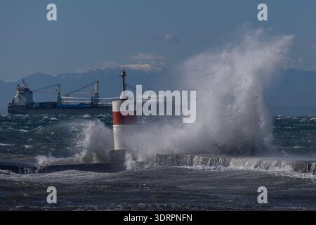 Une collection de photographies côtières spectaculaires montrant un cargo naviguant sur une mer agitée, de puissantes vagues s'écrasant contre une jetée en béton et un méta Banque D'Images