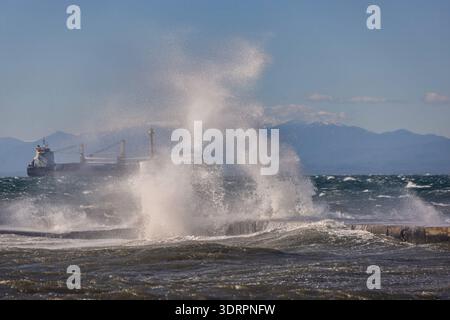 Une collection de photographies côtières spectaculaires montrant un cargo naviguant sur une mer agitée, de puissantes vagues s'écrasant contre une jetée en béton et un méta Banque D'Images