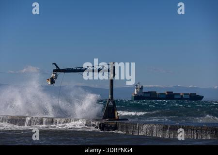 Une collection de photographies côtières spectaculaires montrant un cargo naviguant sur une mer agitée, de puissantes vagues s'écrasant contre une jetée en béton et un méta Banque D'Images