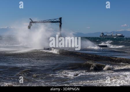 Une collection de photographies côtières spectaculaires montrant un cargo naviguant sur une mer agitée, de puissantes vagues s'écrasant contre une jetée en béton et un méta Banque D'Images