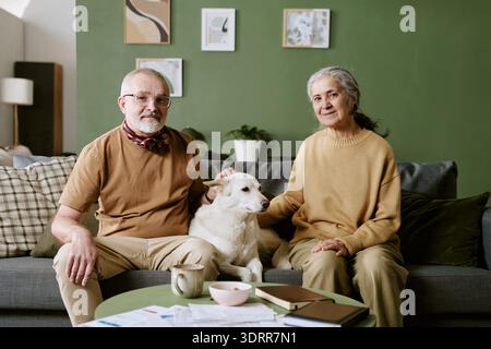 Homme caucasien senior et femme caucasienne senior assis avec chien à l'intérieur Banque D'Images