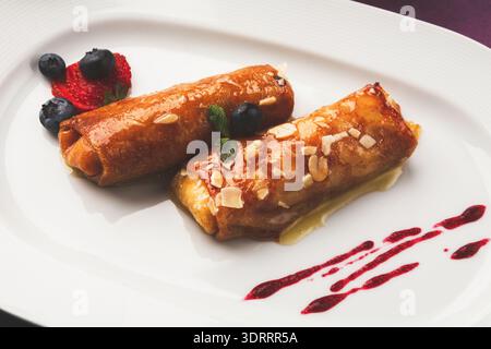 Desserts disposés sur une assiette blanche avec fruits et sauce sur un fond simple Banque D'Images