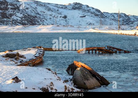 Vieux bateaux submergés dans les rayons du soleil levant. Teriberka, péninsule de Kola, Arctique, Russie Banque D'Images