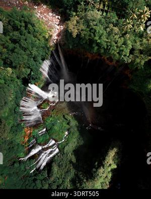 Vue aérienne de Coban Sriti Waterfall descendant les falaises verdoyantes dans un bassin sombre en contrebas, Dampit, Jawa Timur, Indonésie. Banque D'Images
