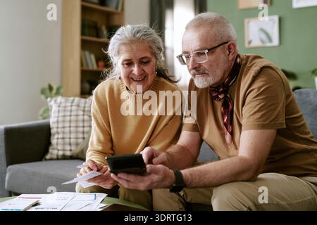 Couple caucasien senior calculant les finances du ménage ensemble à la maison Banque D'Images