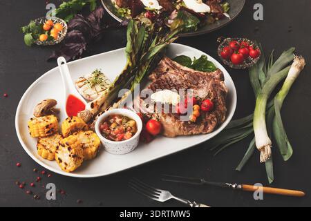 Délicieux repas composé de steak grillé, de légumes et de sauce servis sur une grande assiette blanche Banque D'Images