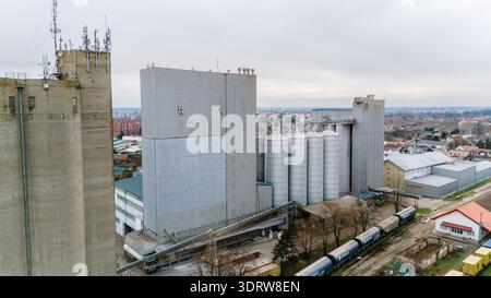 Vue aérienne du complexe industriel, son béton dur contrastant avec les couleurs discrètes de l'étalement urbain environnant, Sremska Mitrovica, Vojvod Banque D'Images