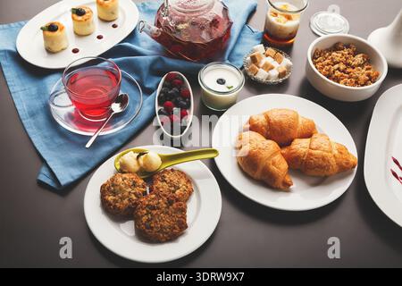Collection de desserts et de boissons affichés sur une table avec un chiffon bleu et une surface sombre Banque D'Images