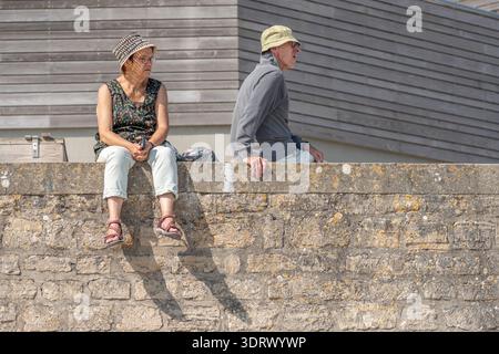 Langrune-sur-mer, France - 08 11 2025 : un couple de personnes âgées assis côte à côte sur le quai, contemplant la mer au loin. Banque D'Images