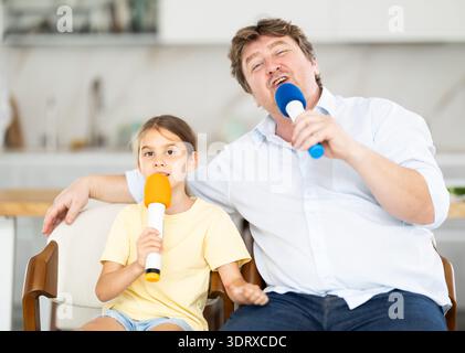 Père et fille chantant karaoké avec des micros Banque D'Images