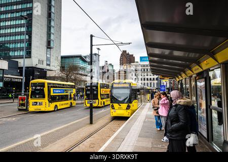 Tramways et bus à impériale Yellow Bee Network à un échangeur de transport très fréquenté dans le centre-ville de Manchester, avec des navetteurs en attente vus le 18 février Banque D'Images