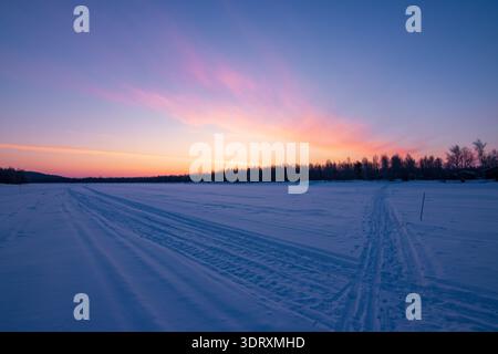 Coucher de soleil sur le lac Inari gelé avec des arbres couverts de neige en Laponie, Finlande près d'Ivalo Banque D'Images