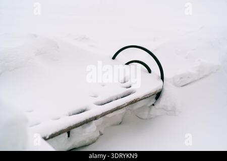 Gros plan minimaliste de Thick Snow Layer sur Metal Park Bench Detail en hiver Banque D'Images