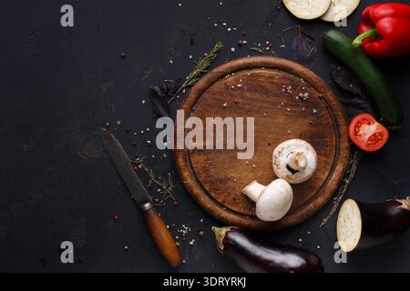 Légumes frais et outils de cuisine disposés sur une planche à découper en bois pour la préparation des repas Banque D'Images