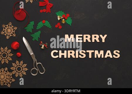 Collage joyeux Noël avec ciseaux, décorations et objets d'artisanat disposés sur une table sombre Banque D'Images