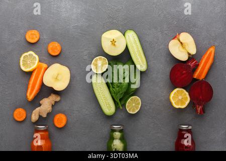 Arrangement coloré de fruits et légumes frais sur une surface grise avec des bouteilles de jus Banque D'Images