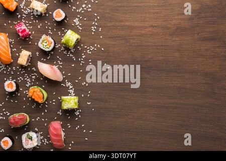 Variété de Sushi disposés sur une table en bois avec du riz dispersé autour Banque D'Images
