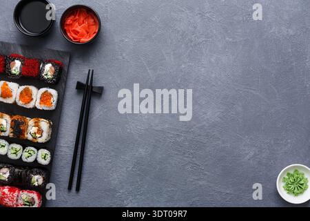 Variété colorée de Sushi servi avec du gingembre et du wasabi sur une table sombre Banque D'Images