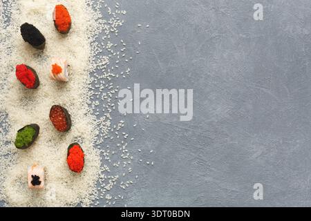 Variété de pièces de Sushi disposées sur fond de riz blanc et gris Banque D'Images