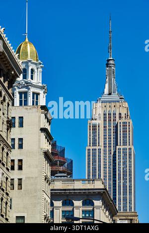 L'Empire State Building s'élève au-dessus des bâtiments de Manhattan. Le soleil brille sur ce célèbre monument New-yorkais. Banque D'Images
