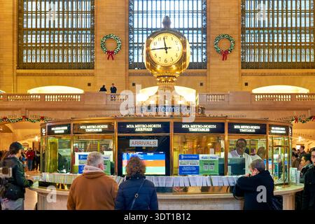 Les gens attendent au kiosque d'information dans Grand Central terminal. La grande horloge se trouve au-dessus lorsque les voyageurs cherchent des informations sur les trains. Banque D'Images