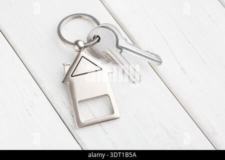 Porte-clés avec étiquette en forme de maison et clé sur la surface en bois Banque D'Images
