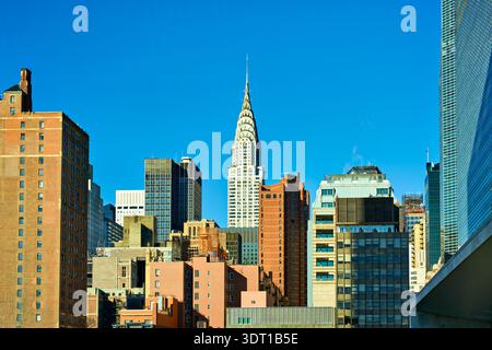 Chrysler Building est visible parmi les différents bâtiments de Manhattan. C'est un jour de ciel bleu clair à New York City avec la lumière du soleil qui brille. Banque D'Images