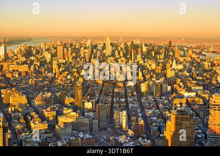 Vue de Manhattan à New York City avec de hauts bâtiments et rues. La scène capture la ville pendant le coucher du soleil avec une lueur orange. Banque D'Images