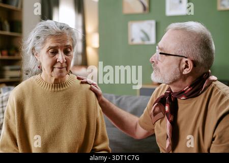 Homme caucasien senior réconfortant femme caucasienne senior dans le salon Banque D'Images