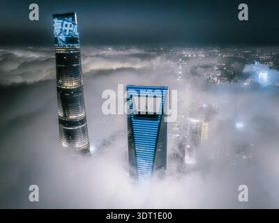 Vue aérienne de gratte-ciel traversant une mer de brouillard éthérée, leurs sommets illuminés contrastant avec le ciel sombre, Shanghai, Chine. Banque D'Images