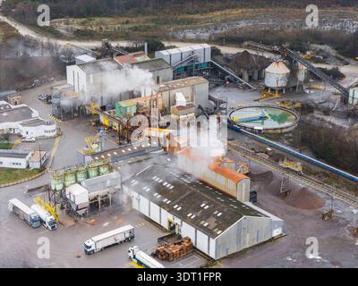 Vue aérienne d'un complexe industriel avec des panaches de fumée s'élevant au milieu de bâtiments durs et de machinerie lourde, Glomel, Bretagne, France. Banque D'Images