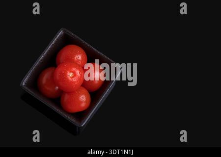 Tomates cerises mûres dans un petit bol sur fond sombre Banque D'Images