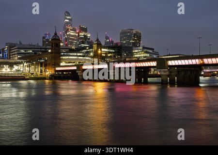 Vue nocturne sur les gratte-ciel illuminés de Londres avec ses gratte-ciel modernes. Les lumières vibrantes de la ville se reflètent sur la Tamise, créant un superbe n urbain Banque D'Images