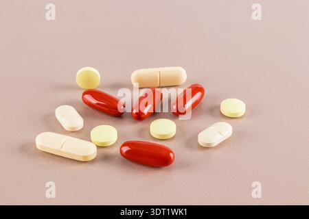 Une sélection de différentes pilules et capsules de couleur dispersées sur une surface neutre, représentant une variété de médicaments généralement utilisés dans les soins de santé Banque D'Images