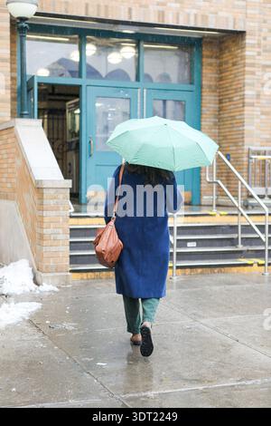 Femme avec parapluie vert marche dans la station de métro à Brooklyn Banque D'Images