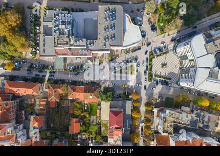 Vue aérienne de haut en bas d'un carrefour urbain animé à Pogradec, Albanie, montrant des rues, des voitures garées, des toits, et arbres d'automne. Banque D'Images