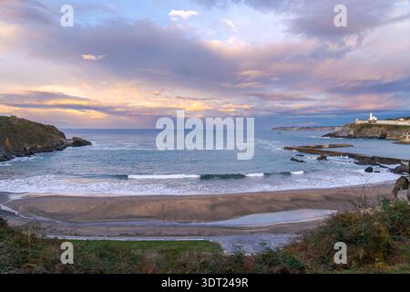 Vue imprenable sur Luarca dans les Asturies, avec une plage sereine, des vagues douces et un ciel de coucher de soleil spectaculaire. Le paysage côtier paisible capture le beau Banque D'Images