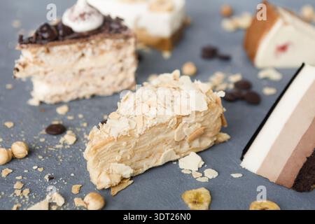 Collection de diverses tranches de dessert disposées sur une surface grise avec des noix et des morceaux de chocolat Banque D'Images