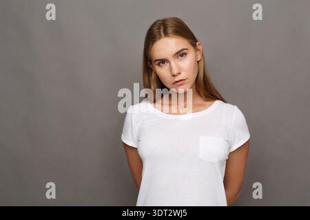 Collection d'images en gros plan montrant une jeune femme dans une chemise blanche sur un fond gris Banque D'Images