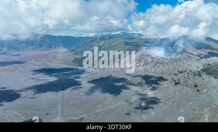 Vue imprenable sur le cratère fumant bromo au milieu de pics accidentés et de vallées brumeuses. Des cieux vibrants soulignent le drame volcanique surréaliste en Indonésie. Banque D'Images