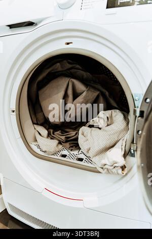 Ouvrez la machine à laver avec une charge de vêtements à l'intérieur du tambour dans un intérieur de maison Banque D'Images
