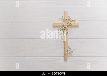 Croix chrétienne en bois décorée de fleurs blanches fraîches de gypsophila. Un symbole religieux de foi, de résurrection et de souvenir pour le copyspace de pâques Banque D'Images