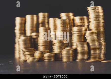 Collection de pièces d'or empilées dans diverses hauteurs sur un fond sombre pendant la lumière du jour Banque D'Images