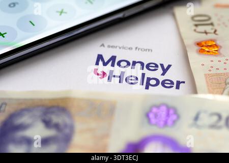Londres. Royaume-Uni- 15 février. 2026. Gros plan d'une calculatrice téléphonique et de billets de banque en livres sterling sur une lettre de Money Helper, un servi soutenu par le gouvernement Banque D'Images