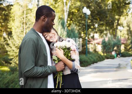 Couple profite d'un moment avec des fleurs dans un parc pendant la journée dans un cadre magnifique Banque D'Images