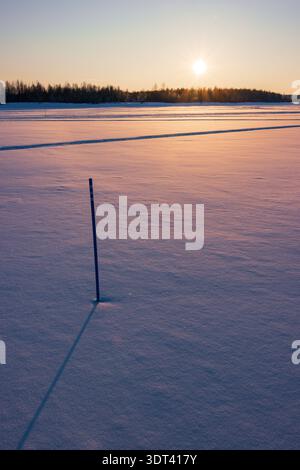 Coucher de soleil sur le lac Inari gelé avec des arbres couverts de neige en Laponie, Finlande près d'Ivalo Banque D'Images