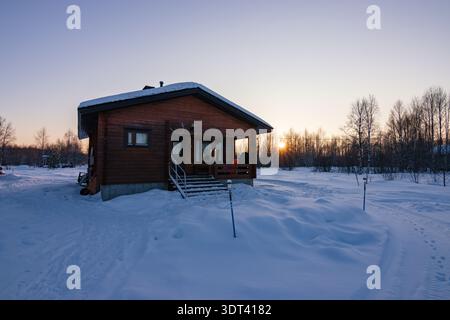 Coucher de soleil sur le lac Inari gelé avec des arbres couverts de neige en Laponie, Finlande près d'Ivalo Banque D'Images