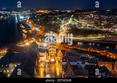 Vue aérienne sur le Burgtor gothique, porte médiévale de la ville nord de la ville hanséatique Lübeck, illuminée la nuit, Schleswig-Holstein, Allemagne Banque D'Images