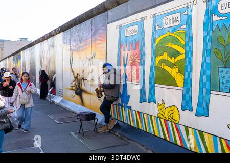 Berlin Allemagne - septembre 27 2025 : un homme jouant du saxophone devant le mur de Berlin en Allemagne Banque D'Images