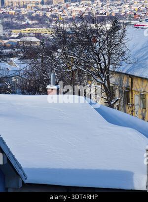 Une vue détaillée des épaisses couches de neige sur les toits d'une maison dans un quartier résidentiel après un lourd blizzard hivernal. Banque D'Images
